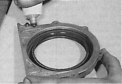 Applying a thin layer of sealant to the mating surface of the crankshaft rear cover on 6-cylinder…
