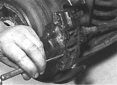 Using a hammer and appropriate drift to remove the rear brake shoe mounting pins