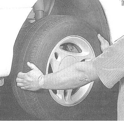 2. Clean the lower end of the steering knuckle. Have an assistant grab the lower edge of the wheel…