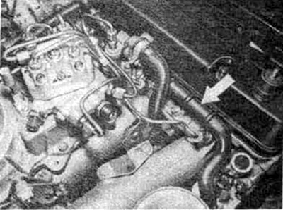 Clamp the additional air damper hose (see arrow), after which the engine idle speed should drop.